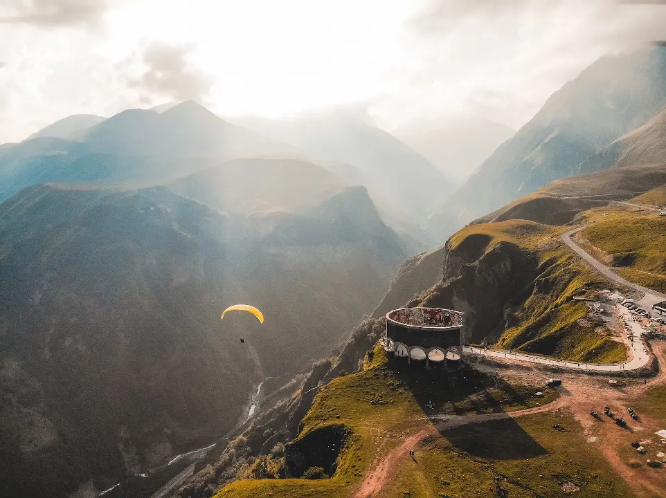 person paragliding on mountain cliff during daytime